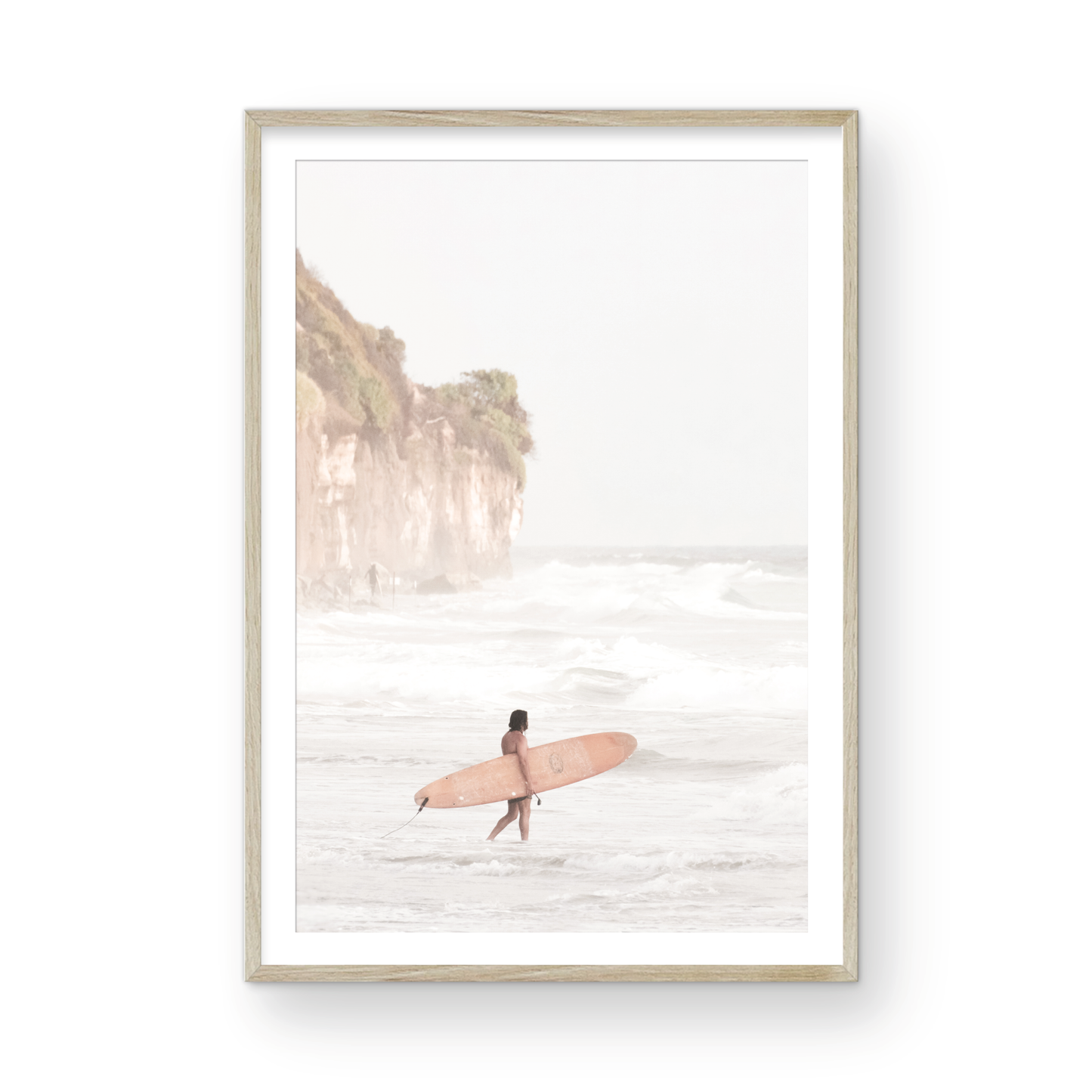 Vertical surf art print of a lone surfer carrying a surfboard, walking on a rocky, foggy shoreline at Moonlight State Beach with a lifeguard tower and cliff in the background. Photograph in minimalist mock up.