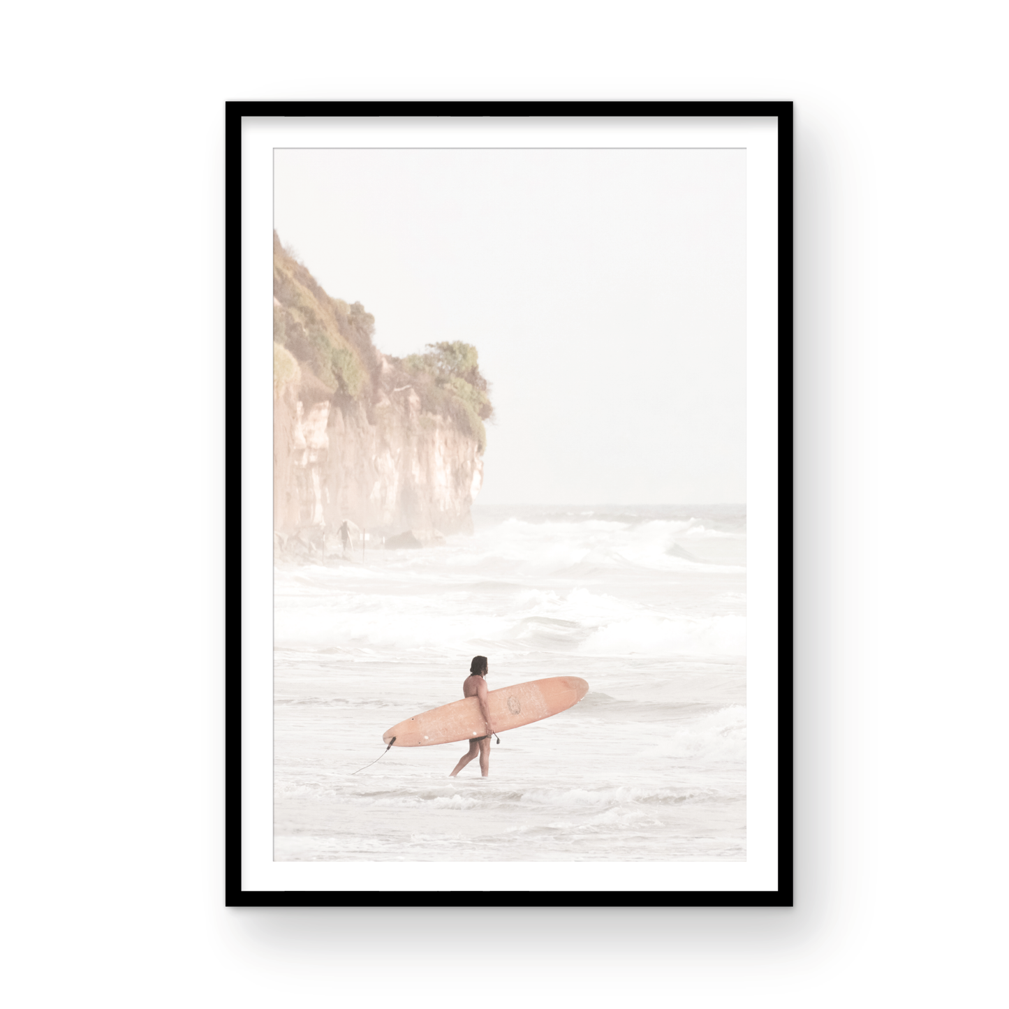 Vertical surf art print of a lone surfer carrying a surfboard, walking on a rocky, foggy shoreline at Moonlight State Beach with a lifeguard tower and cliff in the background. Photograph in minimalist mock up.