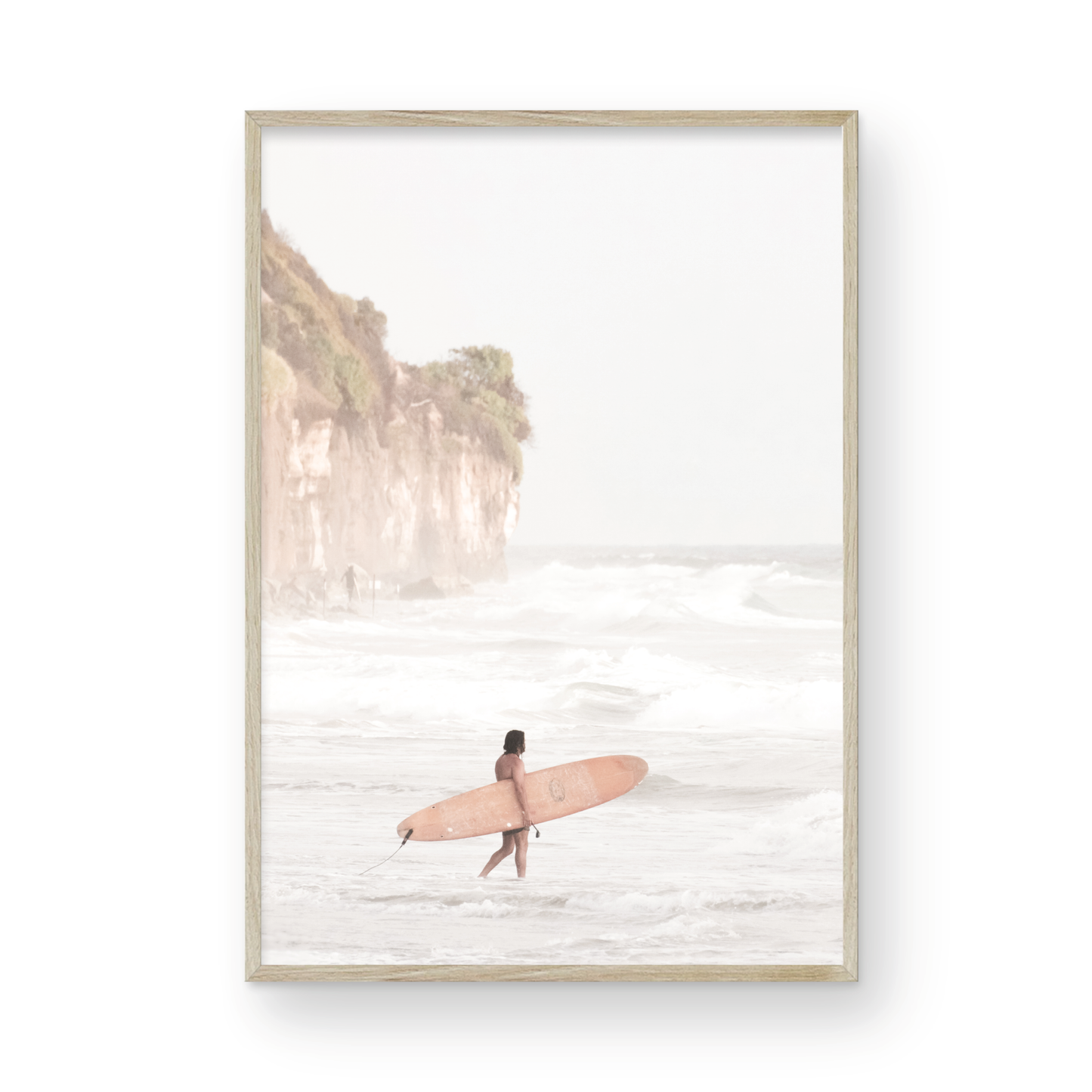 Vertical surf art print of a lone surfer carrying a surfboard, walking on a rocky, foggy shoreline at Moonlight State Beach with a lifeguard tower and cliff in the background. Photograph in minimalist mock up.