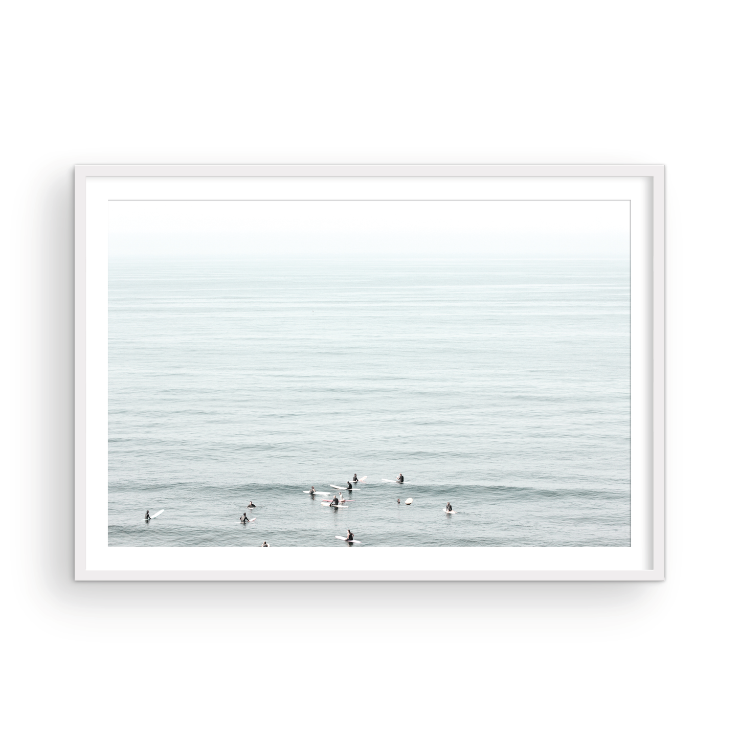 Horizontal surf art showing multiple surfers waiting in the calm ocean water for waves, with a hazy Southern California coastline in the distance. This minimalist surf print captures authentic surf vibes. Photograph in minimalist mock up.