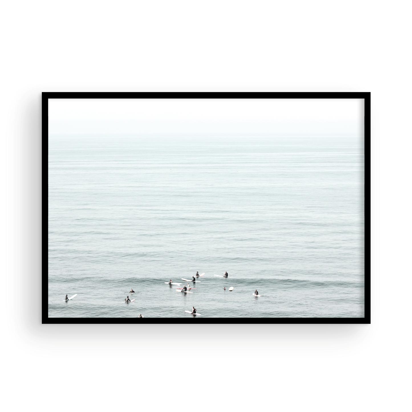 Horizontal surf art showing multiple surfers waiting in the calm ocean water for waves, with a hazy Southern California coastline in the distance. This minimalist surf print captures authentic surf vibes. Photograph in minimalist mock up.