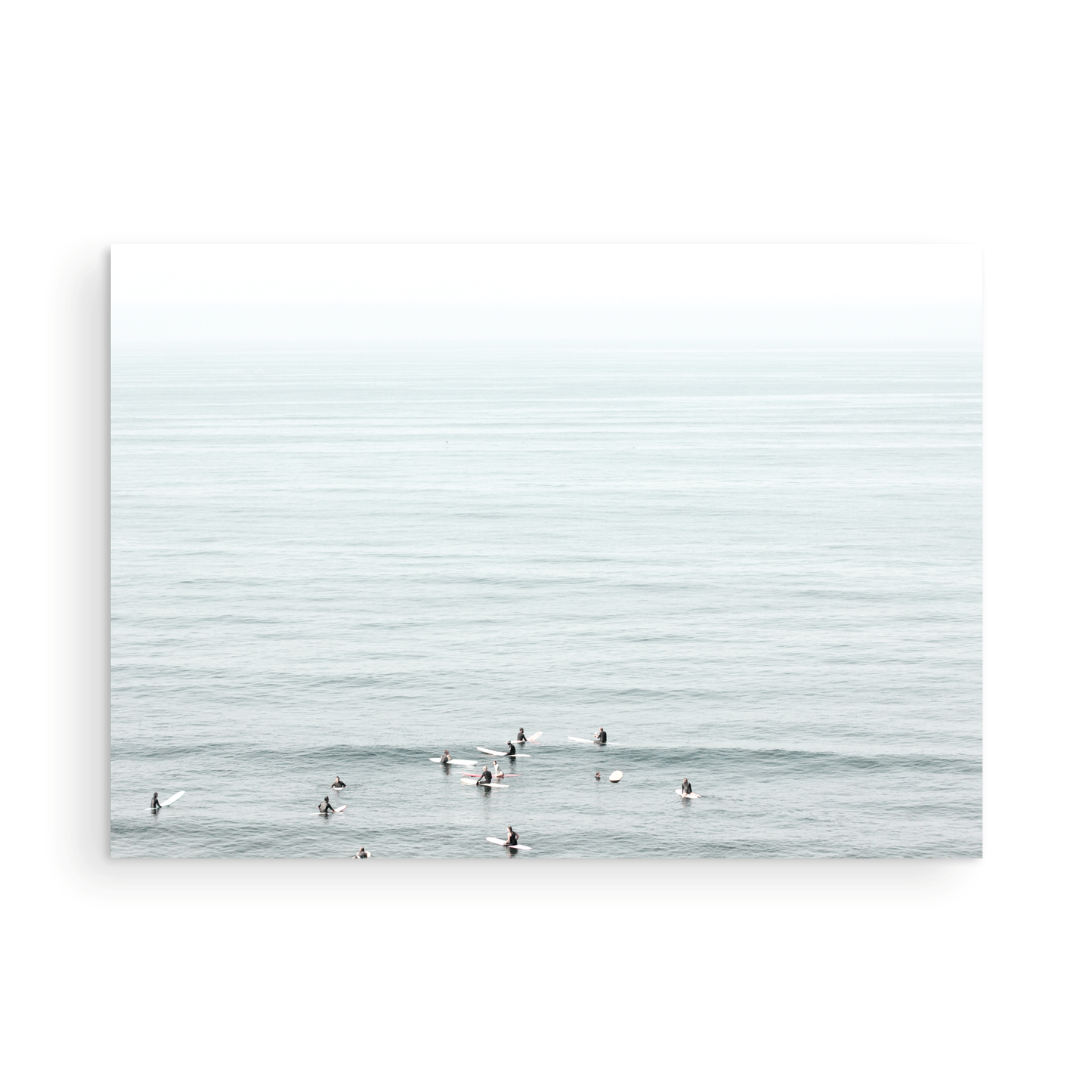 Horizontal surf art showing multiple surfers waiting in the calm ocean water for waves, with a hazy Southern California coastline in the distance. This minimalist surf print captures authentic surf vibes. Photograph in minimalist mock up.