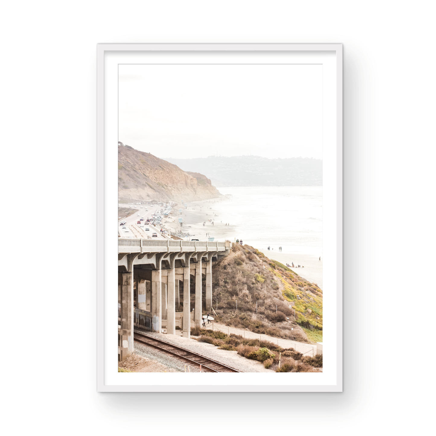 Captivating Torrey Pines San Diego coast scene, presented as vertical beach art. This piece of travel photography features a prominent bridge extending over a wide sandy beach with calm ocean waves. A coastal road winds along the base of rugged cliffs, with a lone coastal palm tree adding a touch of tropical essence to this Southern California seascape print. Photograph in minimalist mock up