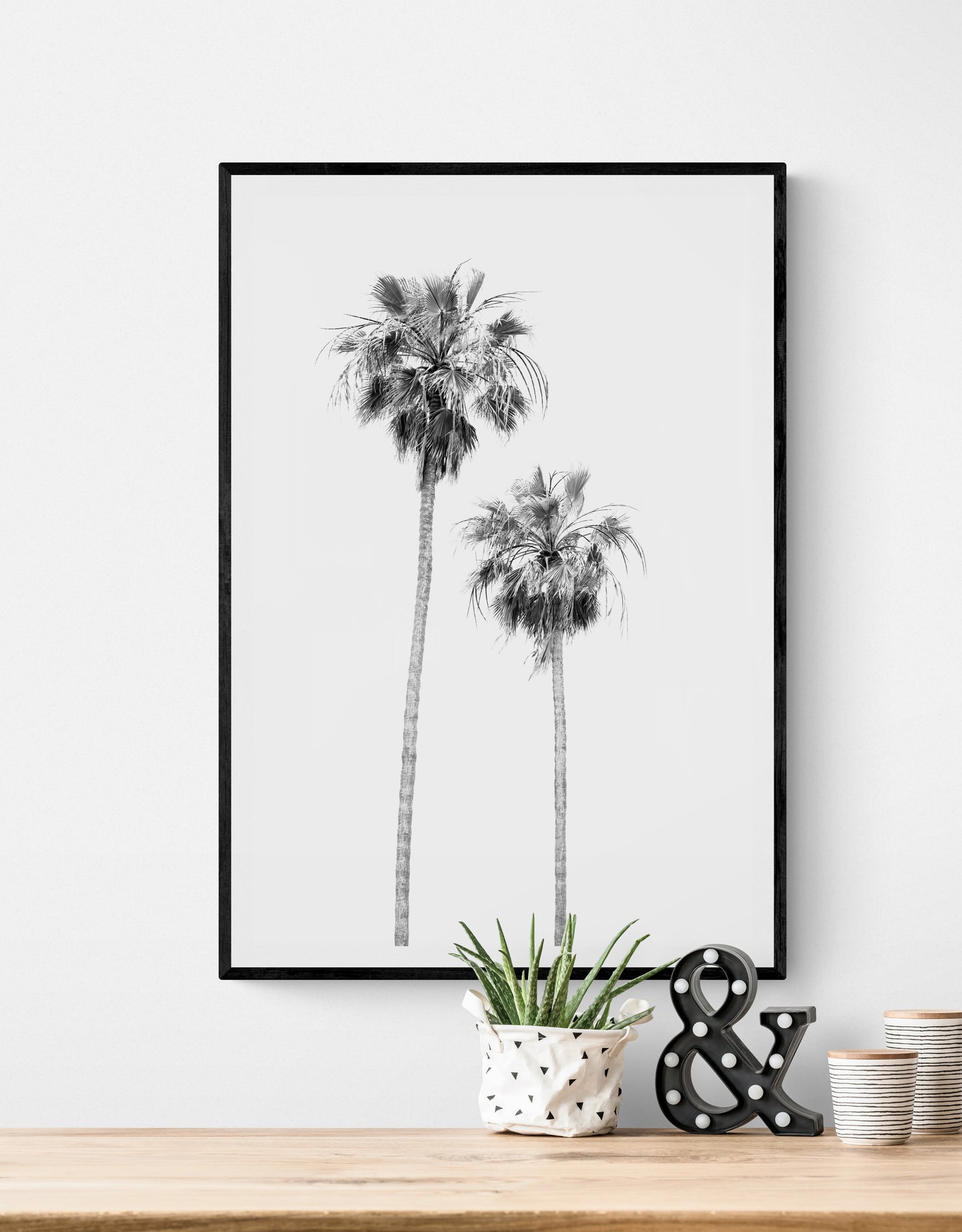 Minimalist palm tree print in black and white, showcasing two tall palm trees against a bright background. This vertical wall art is a coastal palm tree print. Photograph in minimalist mock up.