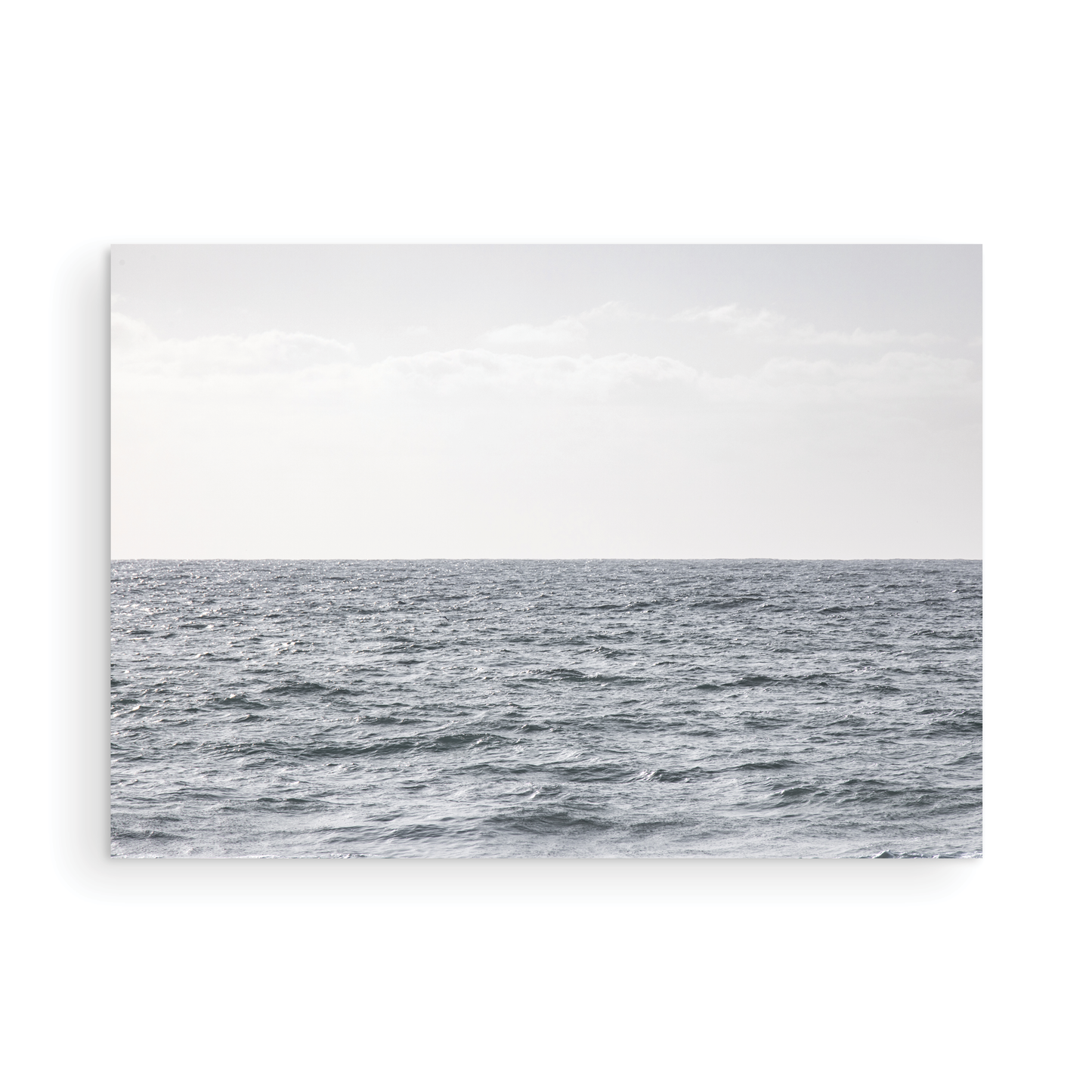 Minimalist ocean print of gentle ocean waves rolling at Moonlight Beach, San Diego, under a bright, soft sky. This calm beach print provides a serene seascape. Photograph in minimalist mock up