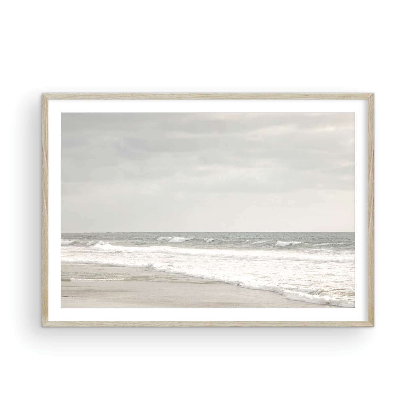 Horizontal minimalist ocean print of gentle ocean waves rolling onto a sandy shoreline at Moonlight Beach, San Diego, under a bright, soft sky. This calm beach print provides a serene seascape. Photograph in minimalist mock up.
