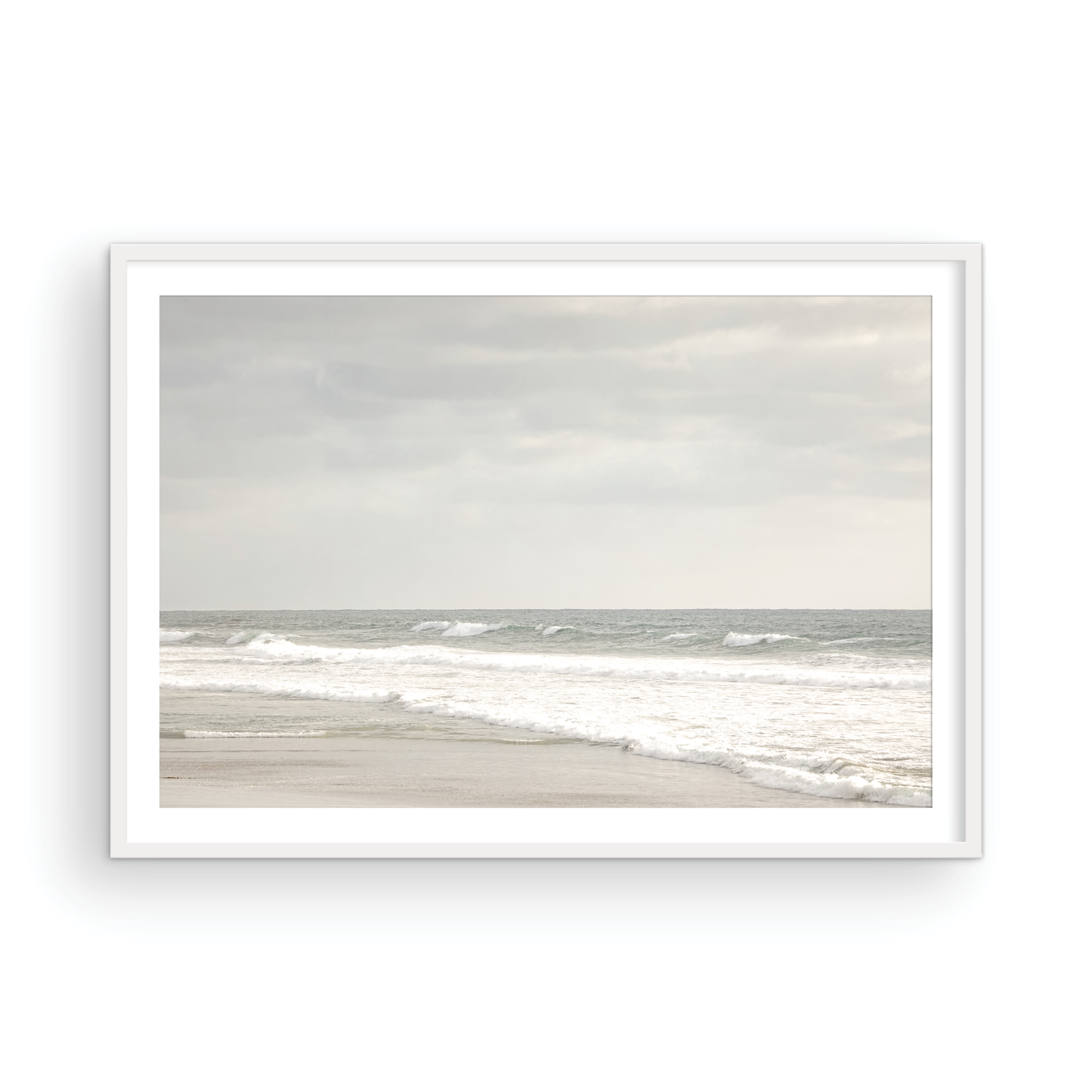 Horizontal minimalist ocean print of gentle ocean waves rolling onto a sandy shoreline at Moonlight Beach, San Diego, under a bright, soft sky. This calm beach print provides a serene seascape. Photograph in minimalist mock up.