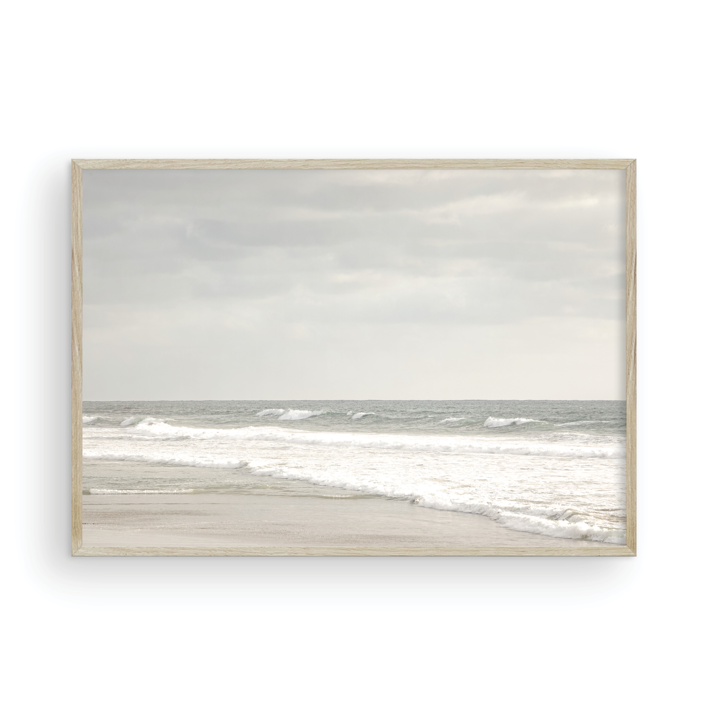 Horizontal minimalist ocean print of gentle ocean waves rolling onto a sandy shoreline at Moonlight Beach, San Diego, under a bright, soft sky. This calm beach print provides a serene seascape. Photograph in minimalist mock up.