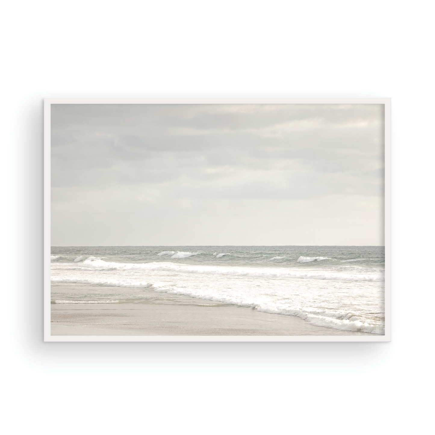 Horizontal minimalist ocean print of gentle ocean waves rolling onto a sandy shoreline at Moonlight Beach, San Diego, under a bright, soft sky. This calm beach print provides a serene seascape. Photograph in minimalist mock up.