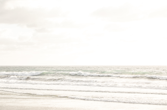 Horizontal minimalist ocean print of gentle ocean waves rolling onto a sandy shoreline at Moonlight Beach, San Diego, under a bright, soft sky. This calm beach print provides a serene seascape.