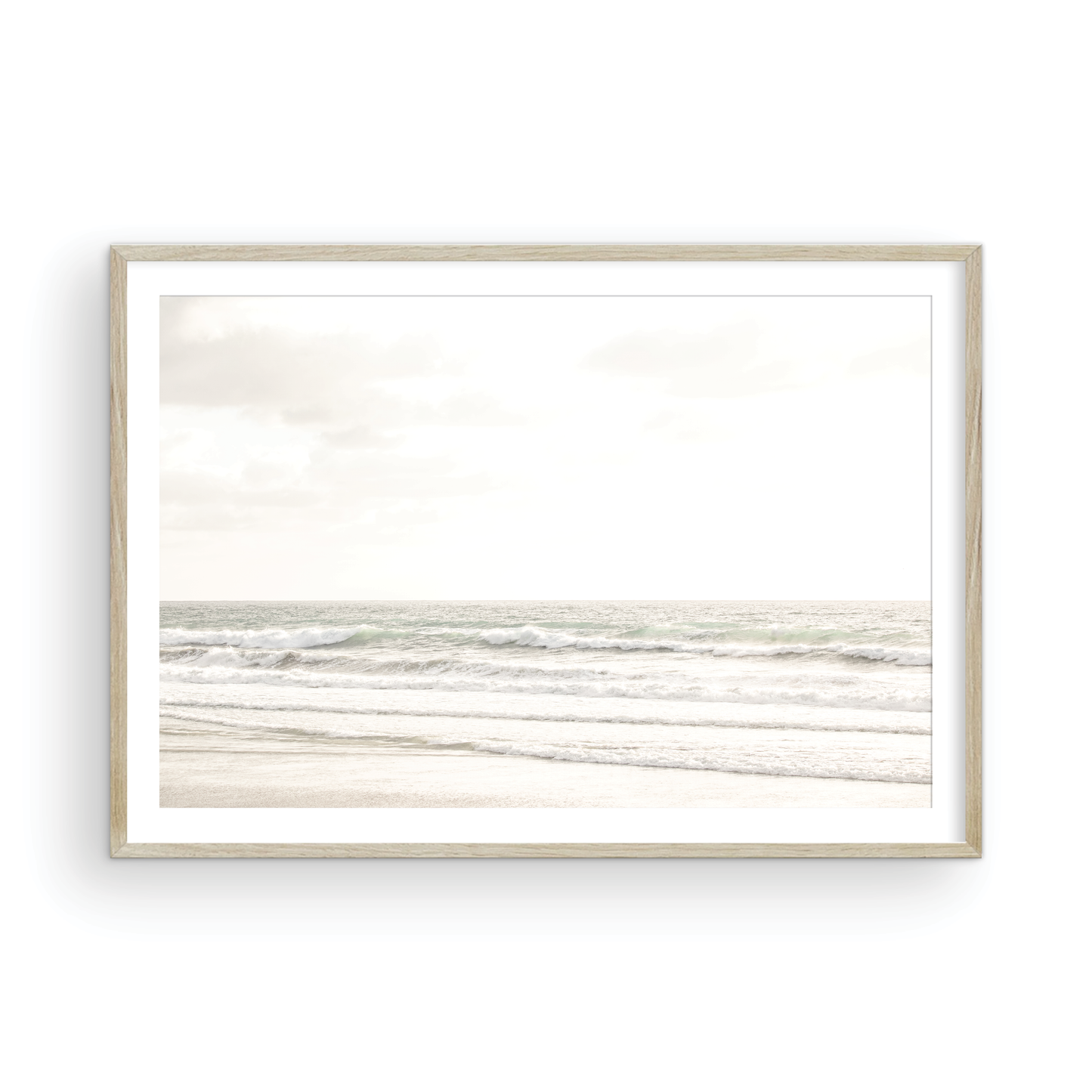 Horizontal minimalist ocean print of gentle ocean waves rolling onto a sandy shoreline at Moonlight Beach, San Diego, under a bright, soft sky. This calm beach print provides a serene seascape. Photograph in minimalist mock up.