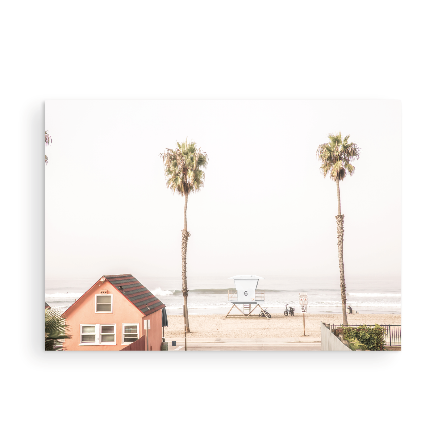 Landscape beach photography of Oceanside, California, highlighting a beachfront house and a lifeguard tower with two tall palm trees and the ocean. Photograph in minimalist mock up.