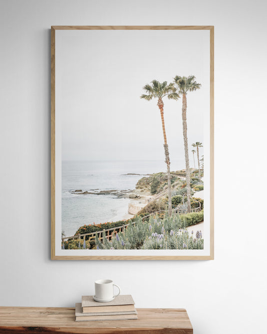 Vertical coastal photography featuring a scenic view of the ocean with palm trees in the background, set against a white sky, located in Laguna California. Photograph in minimalist mock up.