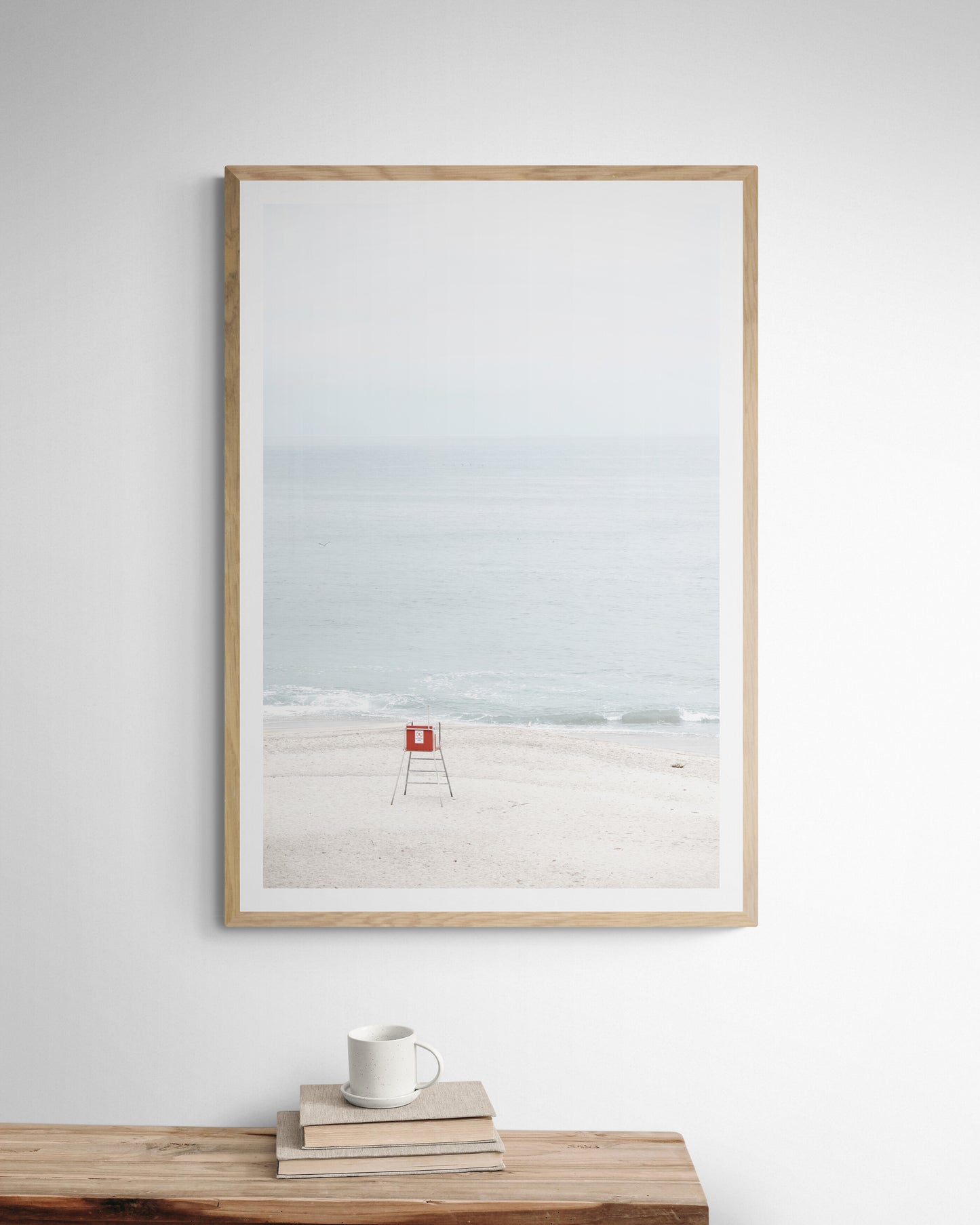 Vertical coastal photography featuring a red and white lifeguard chair and a calm ocean background, located in Laguna California. Photograph in minimalist mock up.