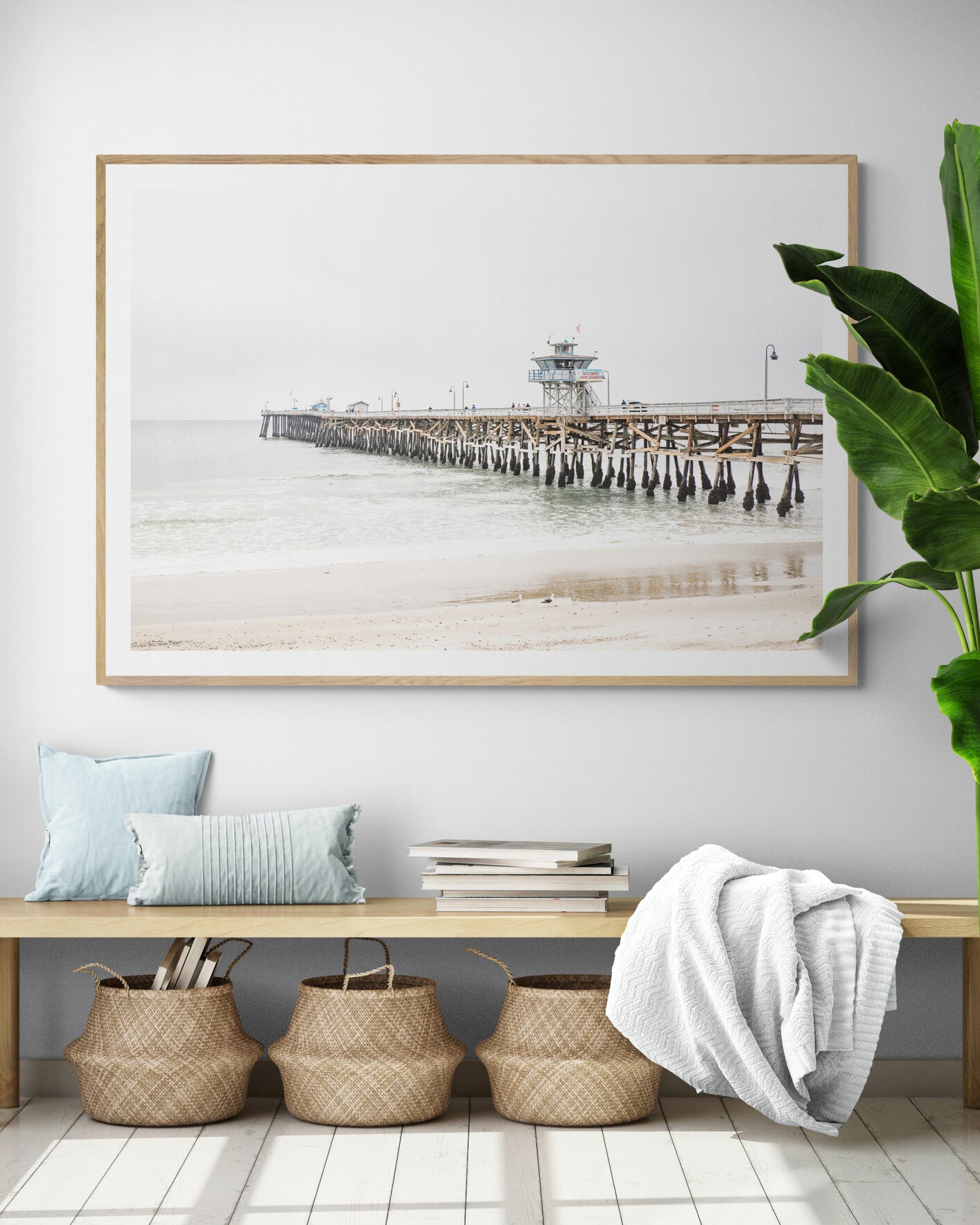 A long wooden pier, the San Clemente Pier, extends into the ocean in this landscape coastal photography. The beach in the foreground suggests a calm ocean print, ideal for a large coastal wall art or a beach cottage wall decor. Photograph in minimalist mock up.
