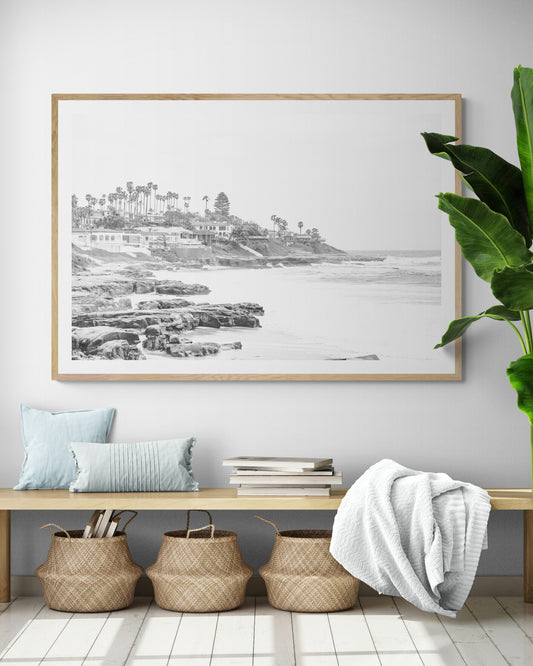Fine art of WindanSea Beach, La Jolla California horizontal landscape black and white print by Southern California photographer Kim Dybczak of Salt Creek Prints, featuring a powerful waves crashing against the rocky shore of California coast. Beach homes and palm trees sit atop the cliffside, with stairs leading down to a sheltered area. Photograph in minimalist entry way mock up