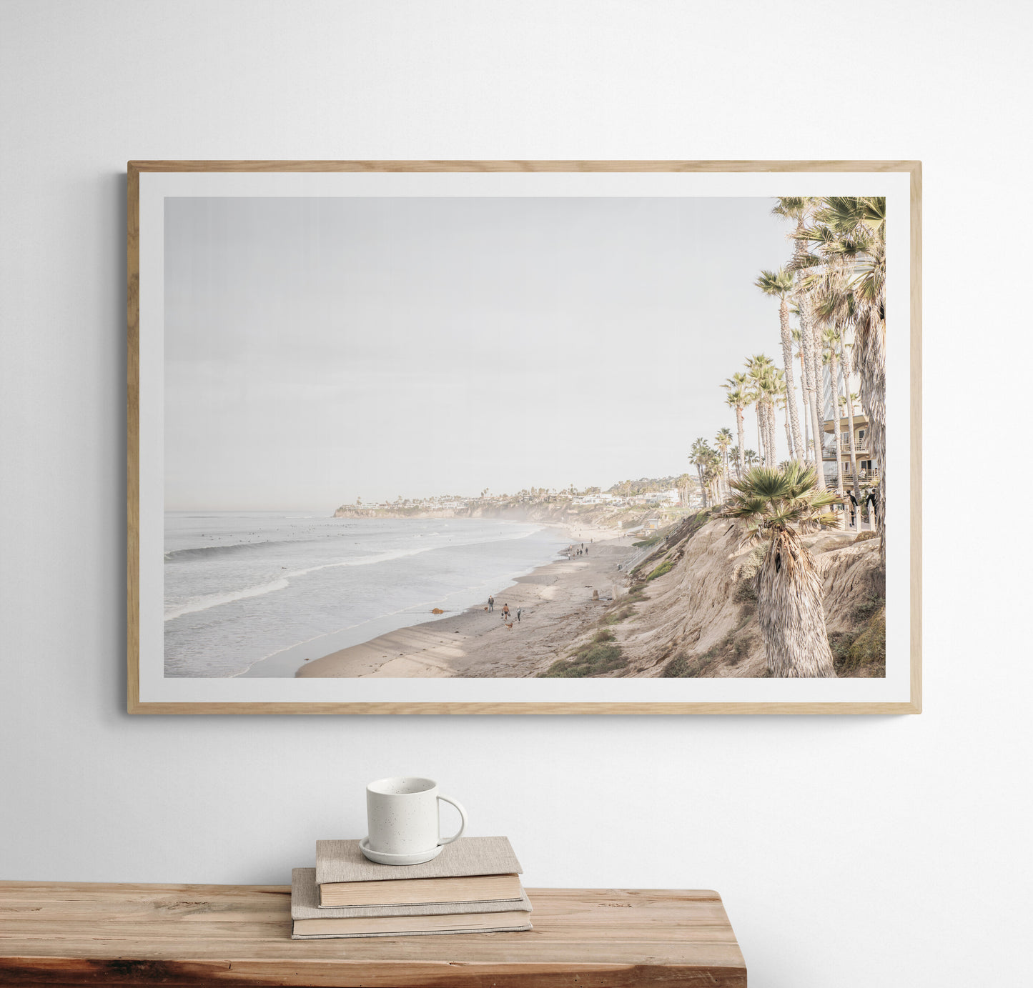 Horizontal, California coast print featuring a high vantage point overlooking Pacific Beach, with tall palm trees, a sandy beach, and the ocean. This coastal print offers a beautiful seascape. Photograph in minimalist mock up.