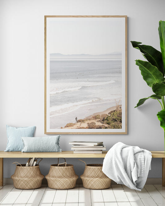 Minimalist ocean print of ocean waves with surfers in the distance and a sandy hillside in the foreground. Photograph in minimalist mock up.