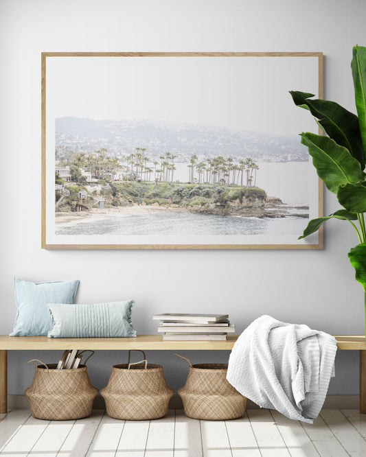 Horizontal coastal photography of Laguna Beach, San Diego, featuring a fine art giclee print featuring palm trees on a small island in a body of water. Photograph in minimalist mock up.