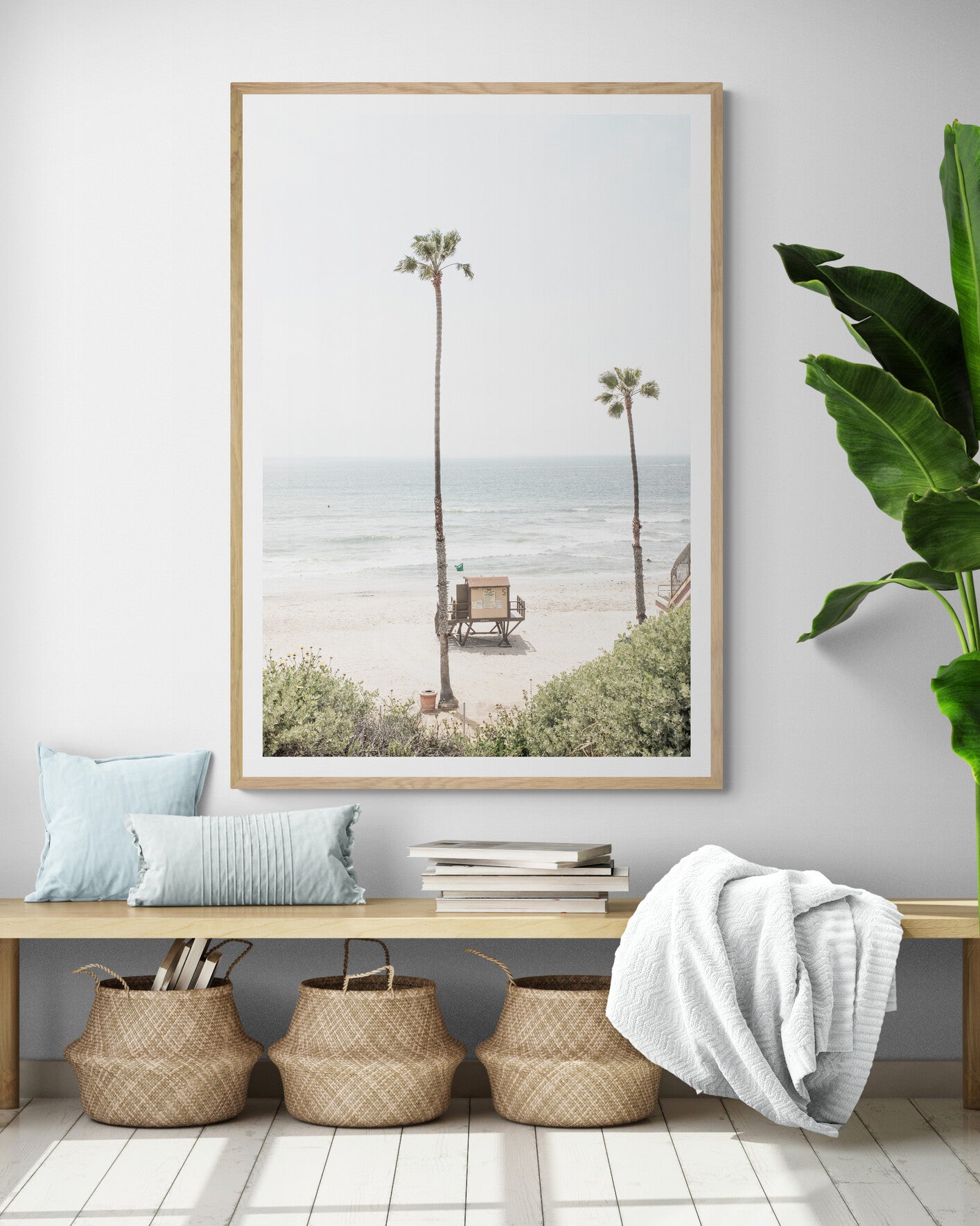 Vertical beach wall art featuring a lifeguard tower nestled between two tall palm trees on a sunny California beach, capturing a serene beach vibe. Photograph in minimalist mock up.