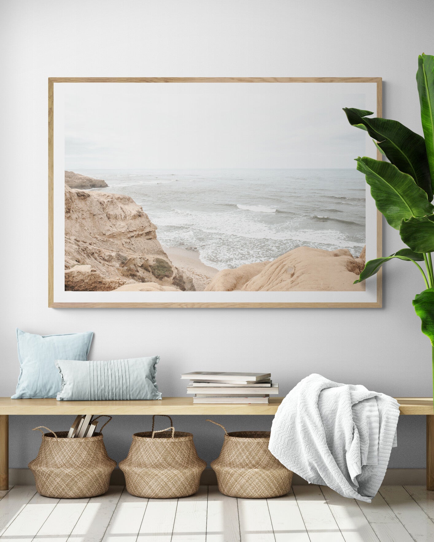 Fine art of Sunset Cliffs, San Diego California horizontal print of hazy high-angle landscape beach photography captures a light blue ocean meeting tall tan and brown cliffs rise as iconic coastal scenery. Photograph in minimalist mock up.