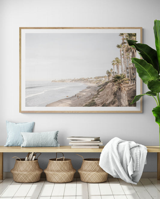 Horizontal, California coast print featuring a high vantage point overlooking Pacific Beach, with tall palm trees, a sandy beach, and the ocean. This coastal print offers a beautiful seascape. Photograph in minimalist mock up.