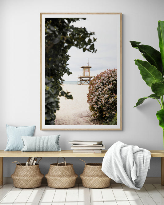 Photography by Kim Dybczak of: A lifeguard tower anchors the coast, set against calm water and open sky.