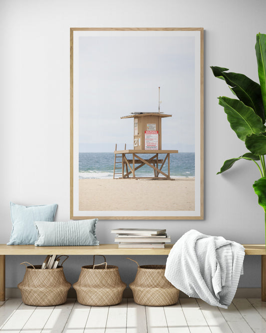 A wide landscape coastal photography view of Newport Beach in Southern California, featuring a lifeguard tower and walls on the beach. Photograph in minimalist mock up.