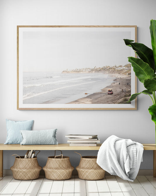 Landscape surf wall decor at Pacific Beach, San Diego, with numerous surfers in the water and a residential cliffside. Photograph in minimalist mock up.
