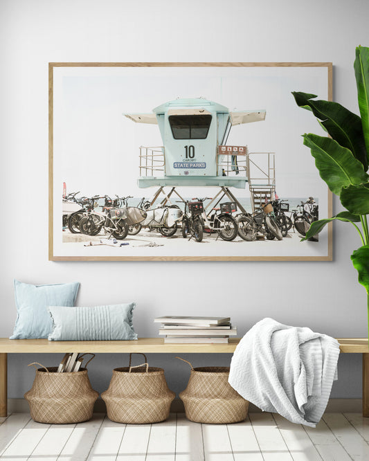 Captured in a horizontal San Diego print, a light blue Lifeguard Tower (number 10) stands prominently among numerous bicycles are parked nearby. Located in Seaside Beach, San Diego, California. Photograph in minimalist mock up.