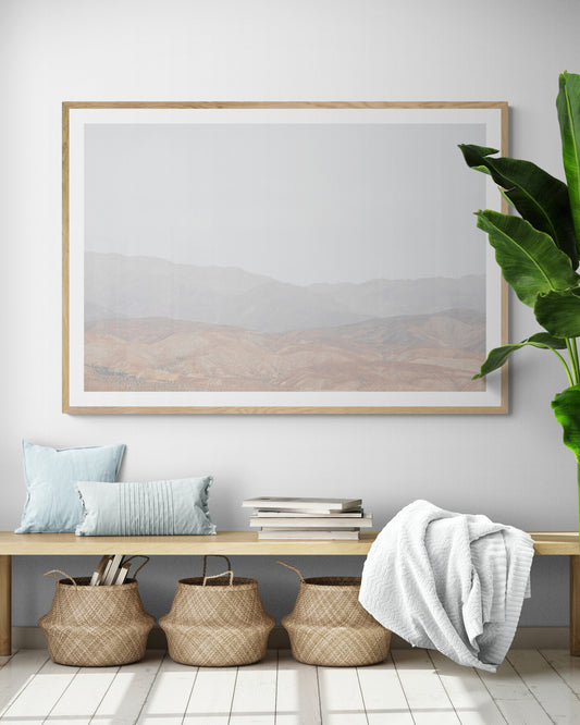 Minimalist art print of hazy mountains layered in soft tones, creating a calm ocean print aesthetic. This horizontal minimalist art print can fit a neutral ocean print theme. Photograph in minimalist mock up.