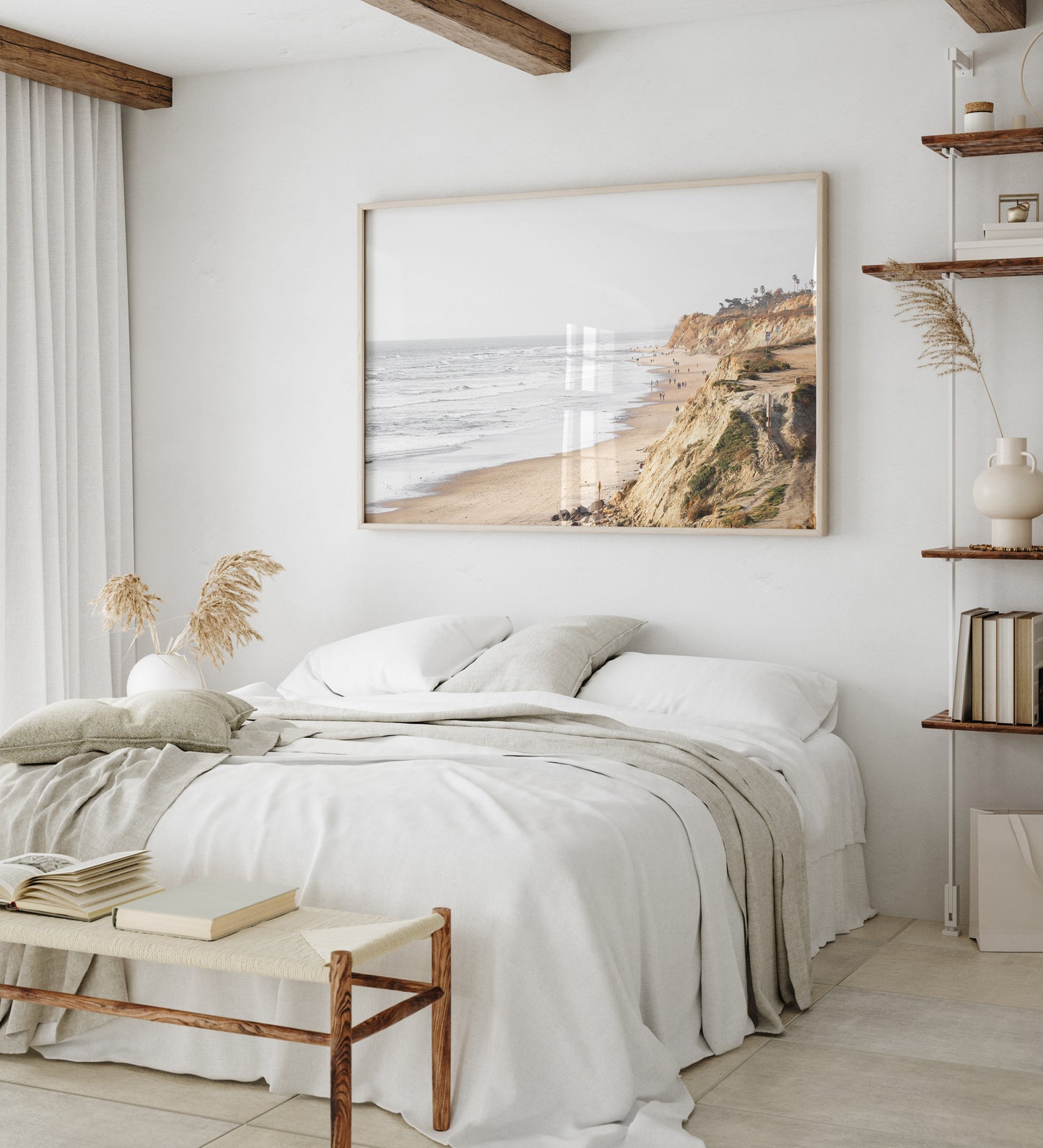 Fine art of Torrey Pines, San Diego California horizontal print of hazy high-angle landscape beach photography captures a light blue ocean meeting a sandy beach with many beach goers. To the right, tall tan and brown cliffs rise as iconic coastal scenery. Photograph in minimalist framed bedroom mock up.