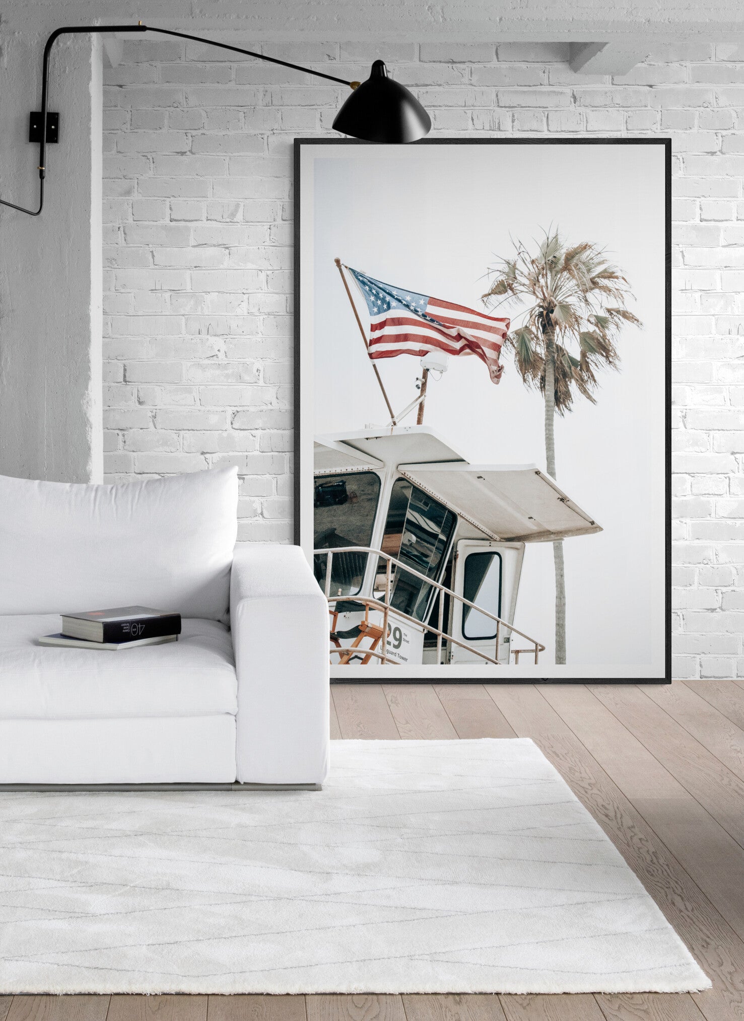 An American flag attached to a lifeguard tower with palm trees in the background, captured in California with a clear sky in the top half of the image. Photograph in minimalist mock up.