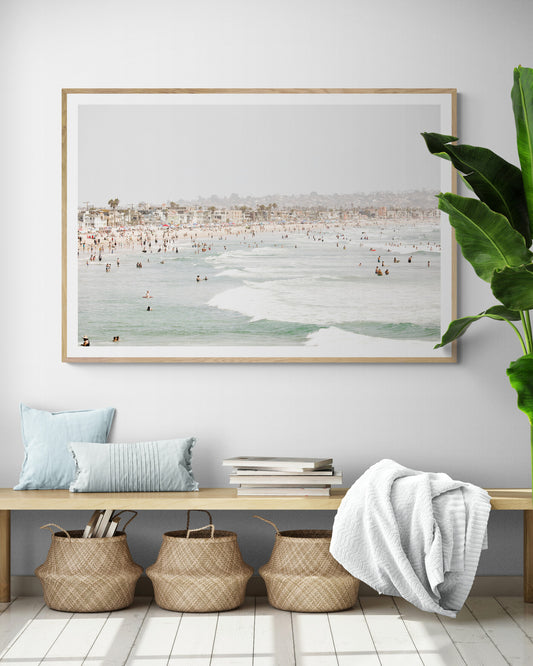Landscape beach photography of a busy San Diego public beach with many people in the sand and ocean waves, a true summer vibes scene. Photograph in minimalist mock up.
