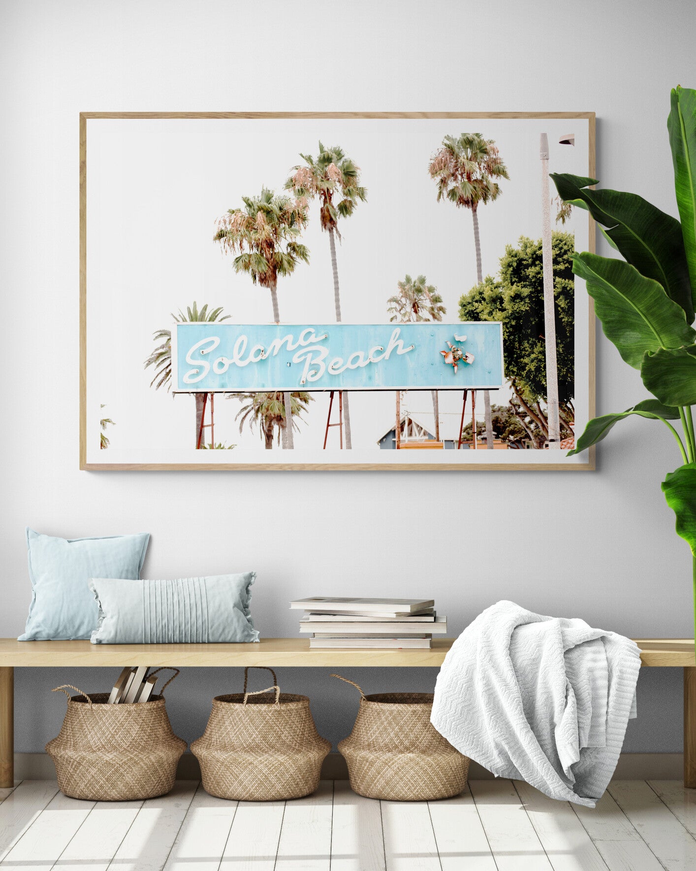 Colorful travel photography capturing the iconic 'Solana Beach' sign, a quintessential piece of Surf Signs San Diego art. The retro light blue sign, adorned with white cursive script and a unique steer head logo, is set against a backdrop of towering palm trees and a bright, hazy California sky. This Southern California surf beach sign evokes strong summer vibes and is perfect for coastal decor. Photograph in minimalist framed entry way mock up.