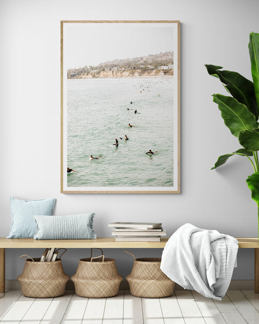 Vertical surf print showing several surfers paddling in the ocean at Pacific Beach, with a distant coastline. This image captures the surfing art of Southern California. Photograph in minimalist mock up.