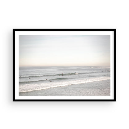 A wide landscape surf wall decor shot of Pacific Beach, showing many surfers in the water catching gentle waves under a hazy sky. This neutral surf print is great for beach art. Photograph in minimalist mock up.
