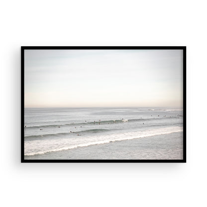 A wide landscape surf wall decor shot of Pacific Beach, showing many surfers in the water catching gentle waves under a hazy sky. This neutral surf print is great for beach art. Photograph in minimalist mock up.