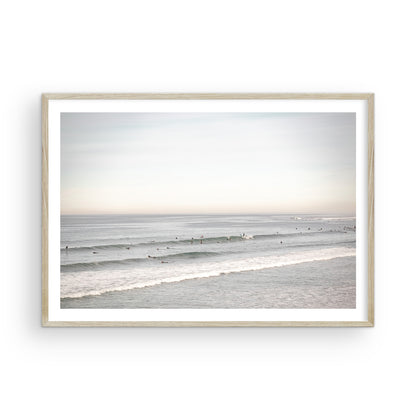A wide landscape surf wall decor shot of Pacific Beach, showing many surfers in the water catching gentle waves under a hazy sky. This neutral surf print is great for beach art. Photograph in minimalist mock up.