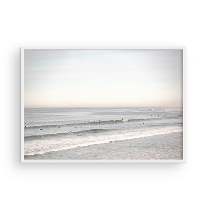 A wide landscape surf wall decor shot of Pacific Beach, showing many surfers in the water catching gentle waves under a hazy sky. This neutral surf print is great for beach art. Photograph in minimalist mock up.