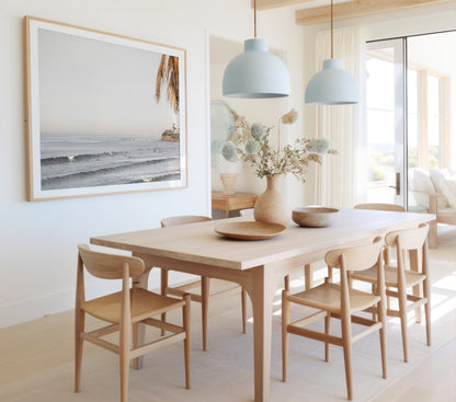 Landscape beach photography of Tourmaline Beach, Pacific Beach, California, with waves and many surfers, framed by a palm tree in the corner. This ocean print captures casual surf vibes. Photograph in minimalist mock up.