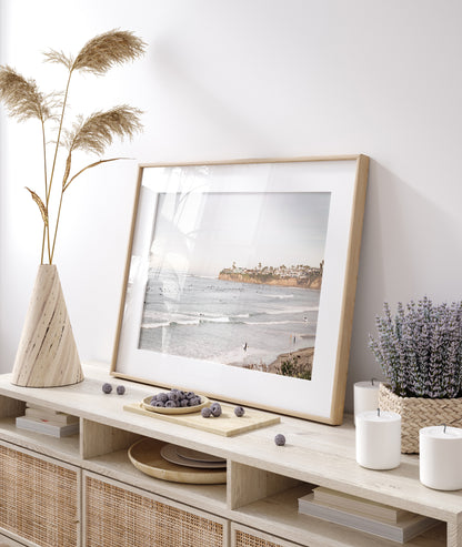 Landscape surf wall decor at Tourmaline Surf Park, Pacific Beach, San Diego, with numerous surfers in the water and a residential cliffside. Photograph in minimalist mock up.