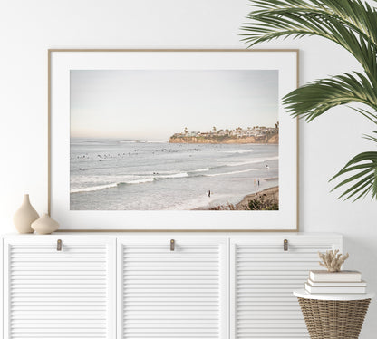 Landscape surf wall decor at Tourmaline Surf Park, Pacific Beach, San Diego, with numerous surfers in the water and a residential cliffside. Photograph in minimalist mock up.