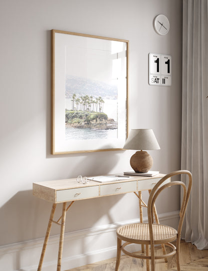 Vertical coastal photography of Laguna Beach, San Diego, featuring a fine art giclee print featuring palm trees on a small island in a body of water. Photograph in minimalist mock up.