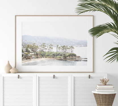 Horizontal coastal photography of Laguna Beach, San Diego, featuring a fine art giclee print featuring palm trees on a small island in a body of water. Photograph in minimalist mock up.