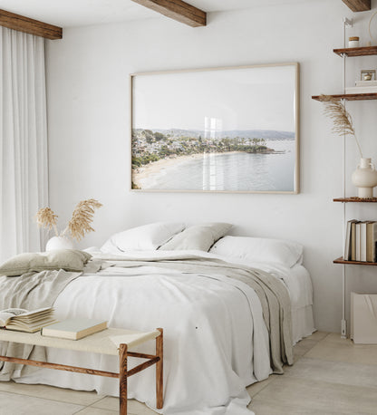 Horizontal coastal photography featuring a beach scene with a calm ocean and beach homes lining the shoreline, located in Laguna California. Photograph in minimalist mock up.