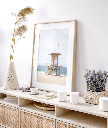 A wide landscape coastal photography view of Newport Beach in Southern California, featuring a lifeguard tower and walls on the beach. Photograph in minimalist mock up.