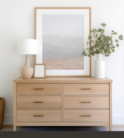 Minimalist art print of hazy mountains layered in soft tones, creating a calm ocean print aesthetic. This vertical minimalist art print can fit a neutral ocean print theme. Photograph in minimalist mock up.