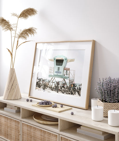 Captured in a horizontal San Diego print, a light blue Lifeguard Tower (number 10) stands prominently among numerous bicycles are parked nearby. Located in Seaside Beach, San Diego, California. Photograph in minimalist mock up.