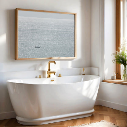 Large minimalist ocean print showing a smooth seascape with gentle ocean waves meeting a clear horizon line, one single sail boat in the distance. This calm nautical print provides a serene view in Dana Point, San Diego, California. Photograph in minimalist mock up.